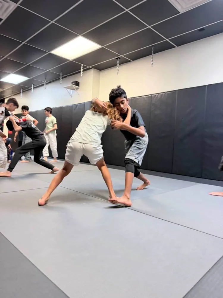 Kids jiu jitsu class with young students practicing wrestling at Lucid Jiu Jitsu